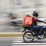 Entregador de moto em avenida