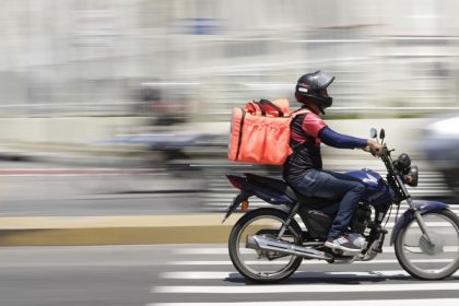 Entregador de moto em avenida