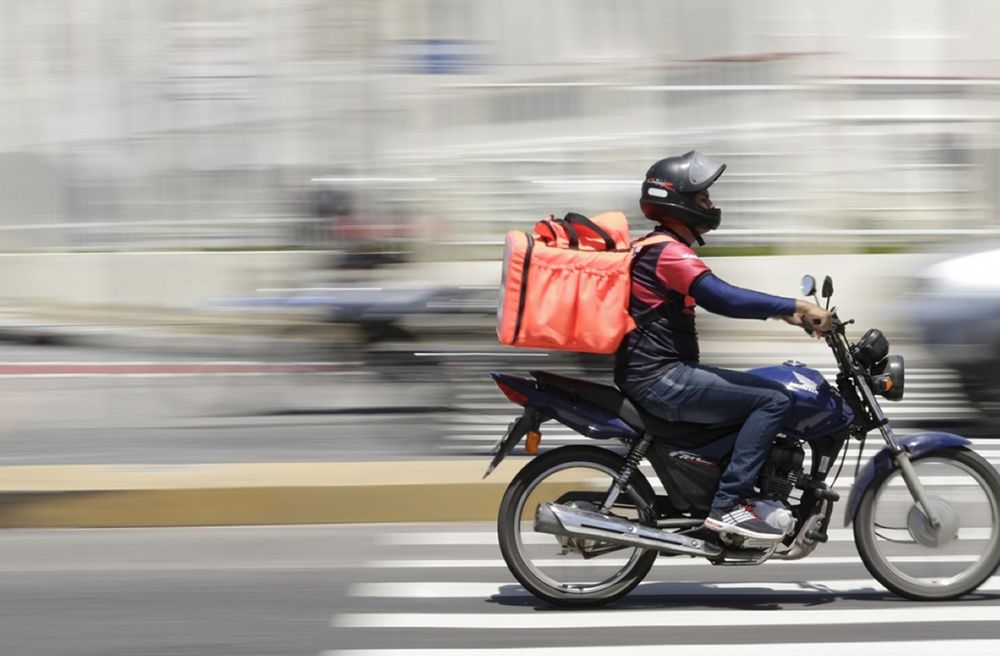 Entregador de moto em avenida